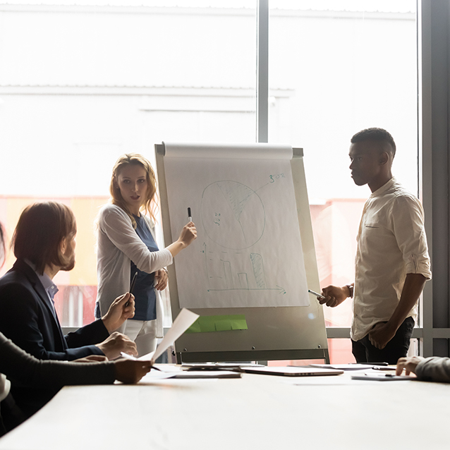 Woman presenting on whiteboard in front of peers