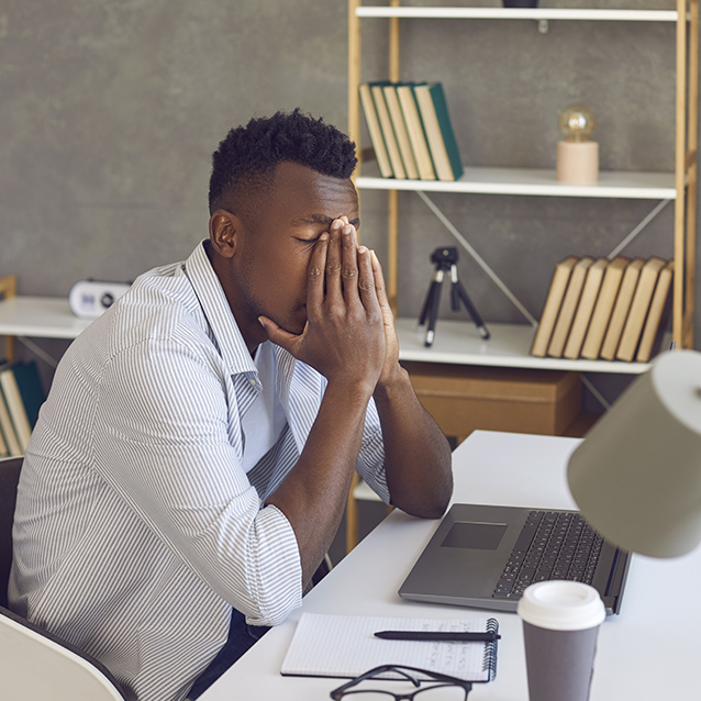 Man overwhelmed in office with hands on face